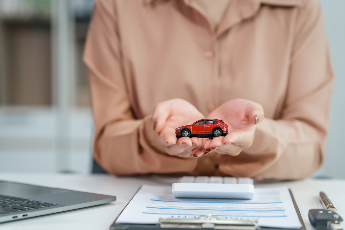 Asian businesswoman negotiates the sale of a car, discussing insurance and financing options, used car loans, premiums, deductibles, and various coverage types to ensure comprehensive protection.