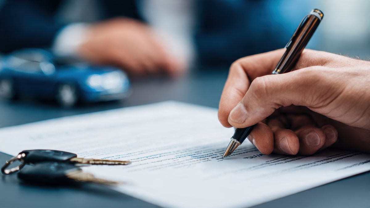 Man signing car insurance document or lease paper. Writing signature on contract or agreement. Buying or selling new or used vehicles. Car keys on table. Warranty or guarantee. Customer or salesman.